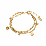 Bracciale a due strati in acciaio oro con piccoli pendenti a forma di dadi e palline.