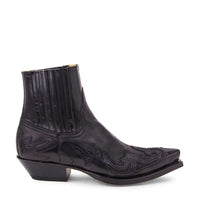 Uno stivaletto western in pelle nera di grande impatto visivo firmato Sendra, caratterizzato da una punta affusolata di grande effetto e da un tacco cubano angolato. Lo stivaletto presenta una finitura lucida e oliata con elaborati ricami in tono e inserti cuciti a forma di fiamma che attraversano la punta, la tomaia e il contrafforte posteriore. In prossimità del collo è presente un elastico laterale, mentre la suola robusta è fissata con la tradizionale cucitura Goodyear a doppia fila.