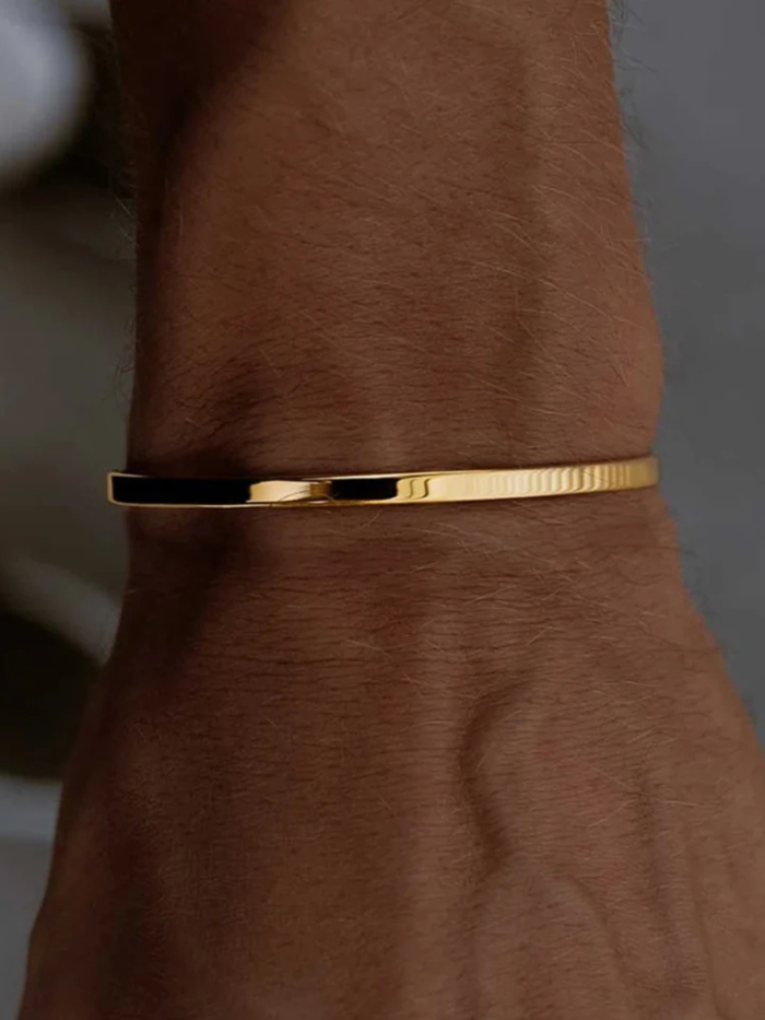 Bracciale rigido aperto color oro indossato al polso, vista ravvicinata