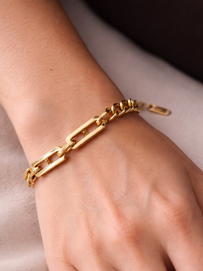 Bracciale dorato a catena con maglie rettangolari indossato al polso