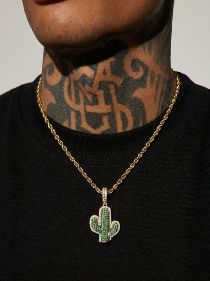 Collana oro con pendente a forma di cactus ricoperto di pietre verdi, indossata su maglia nera