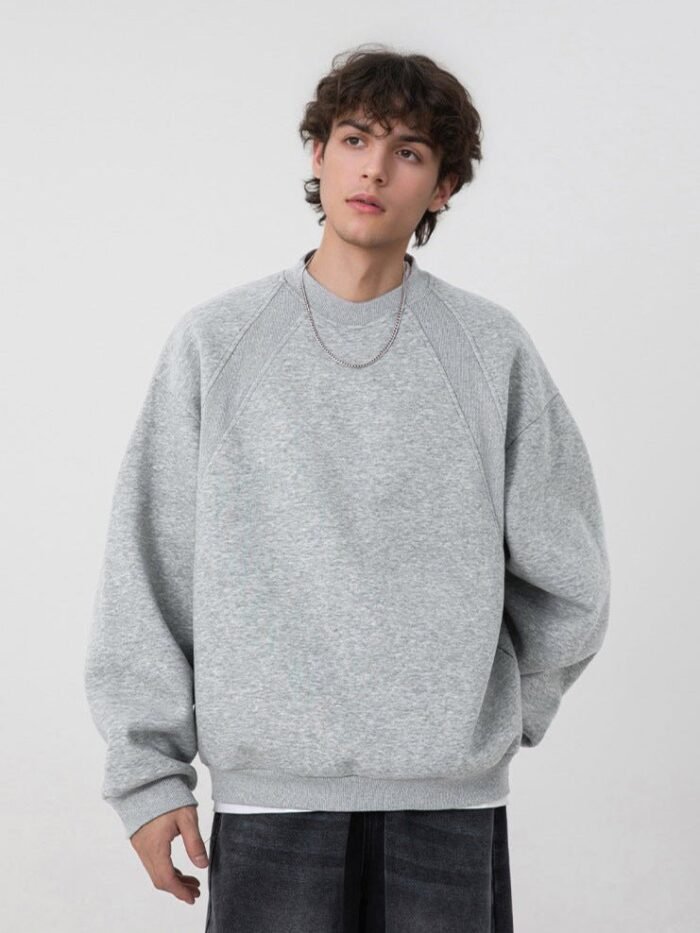 Felpa girocollo semplice grigia con maniche raglan indossata con jeans scuri e catenina
