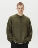 Maglione polo oversized verde oliva con scollo Henley a bottoni indossato da un modello