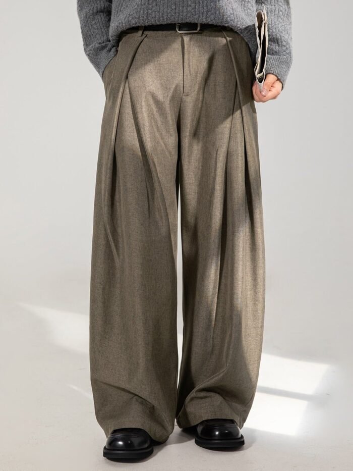 Pantaloni con pinces a gamba larga marroni indossati con maglione grigio e scarpe nere, vista frontale