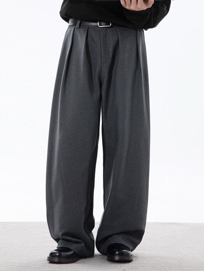 Pantaloni plissettati Osaka Flow grigi a gamba ampia indossati con maglione nero e cintura in pelle, vista frontale