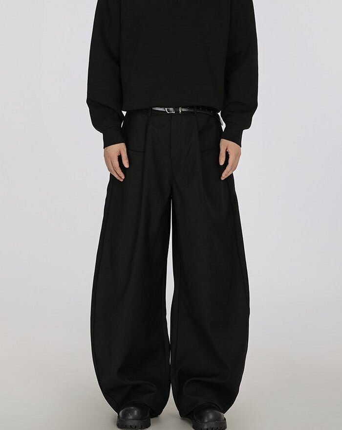 Pantaloni twill neri a gamba larga con pinces, indossati con maglia nera e cintura, vista frontale