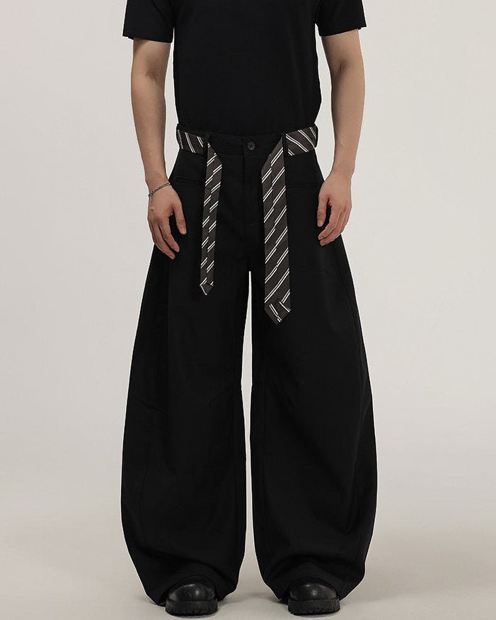 Pantaloni wide-leg da uomo neri con cintura intrecciata a righe annodata in vita, indossati con t-shirt nera