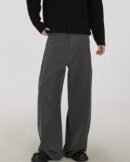 Pantaloni wide-leg stretch grigi da uomo indossati con maglione nero a trecce e scarpe nere, vista frontale