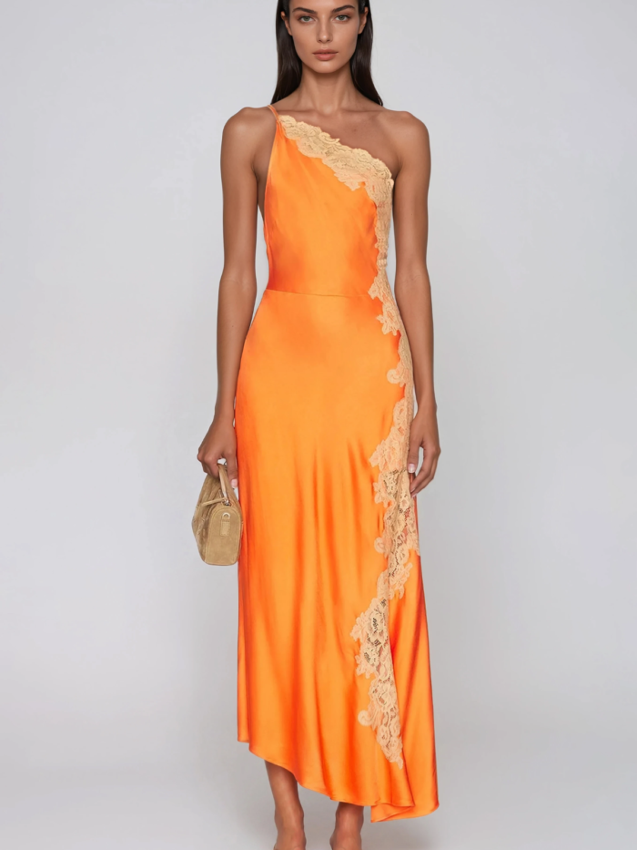 Modella con abito lungo monospalla arancio, pizzo lungo il fianco, borsa in paglia e sandali