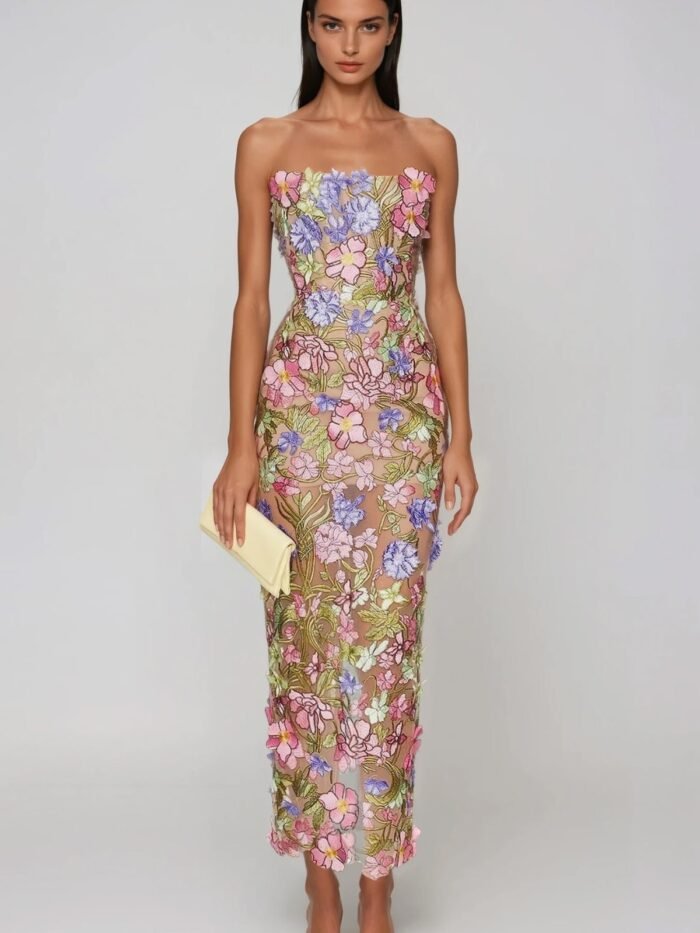 Modella con abito lungo a colonna ricamato a fiori multicolore, pochette chiara e sandali